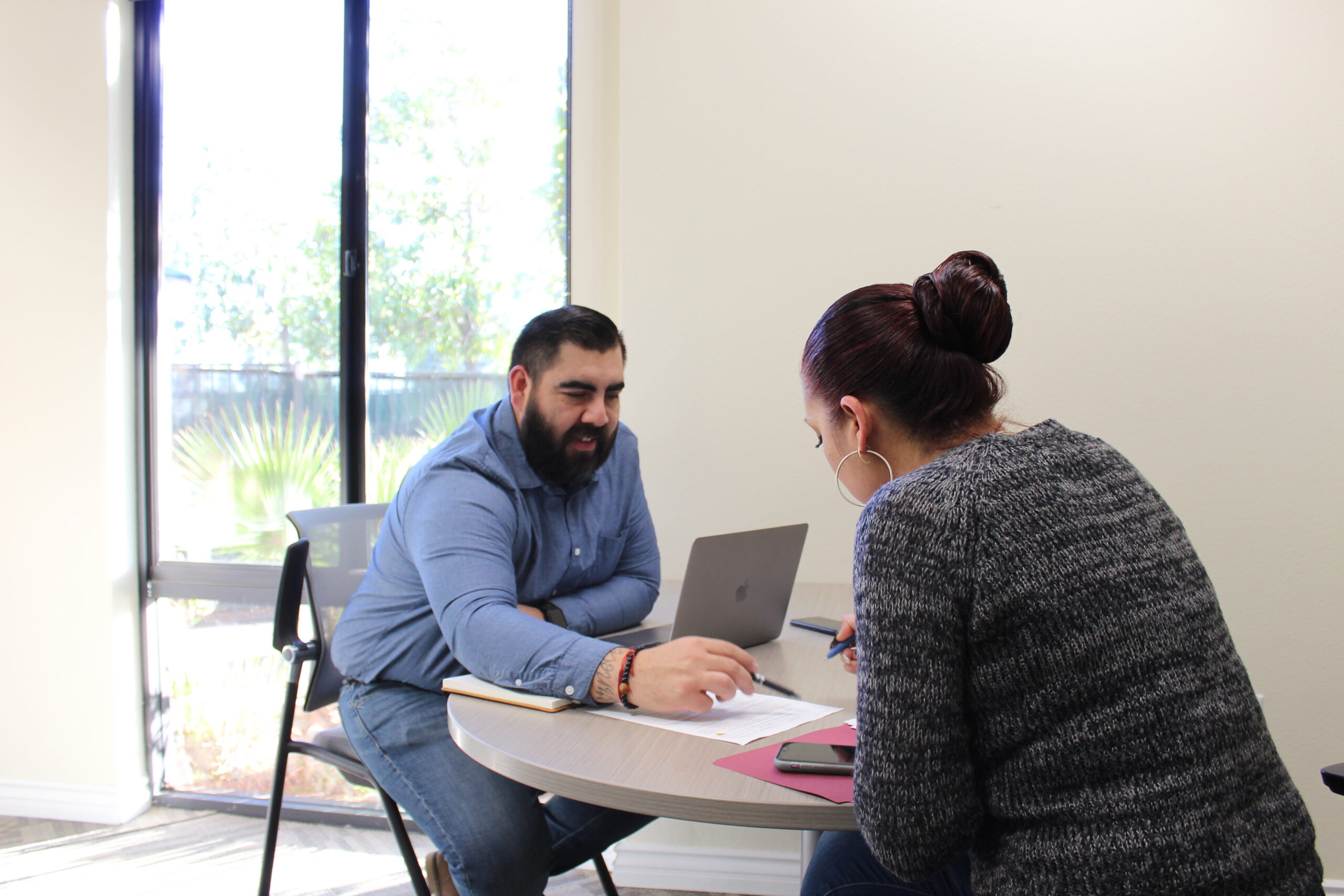 A man and woman sitting at a table with a laptop.